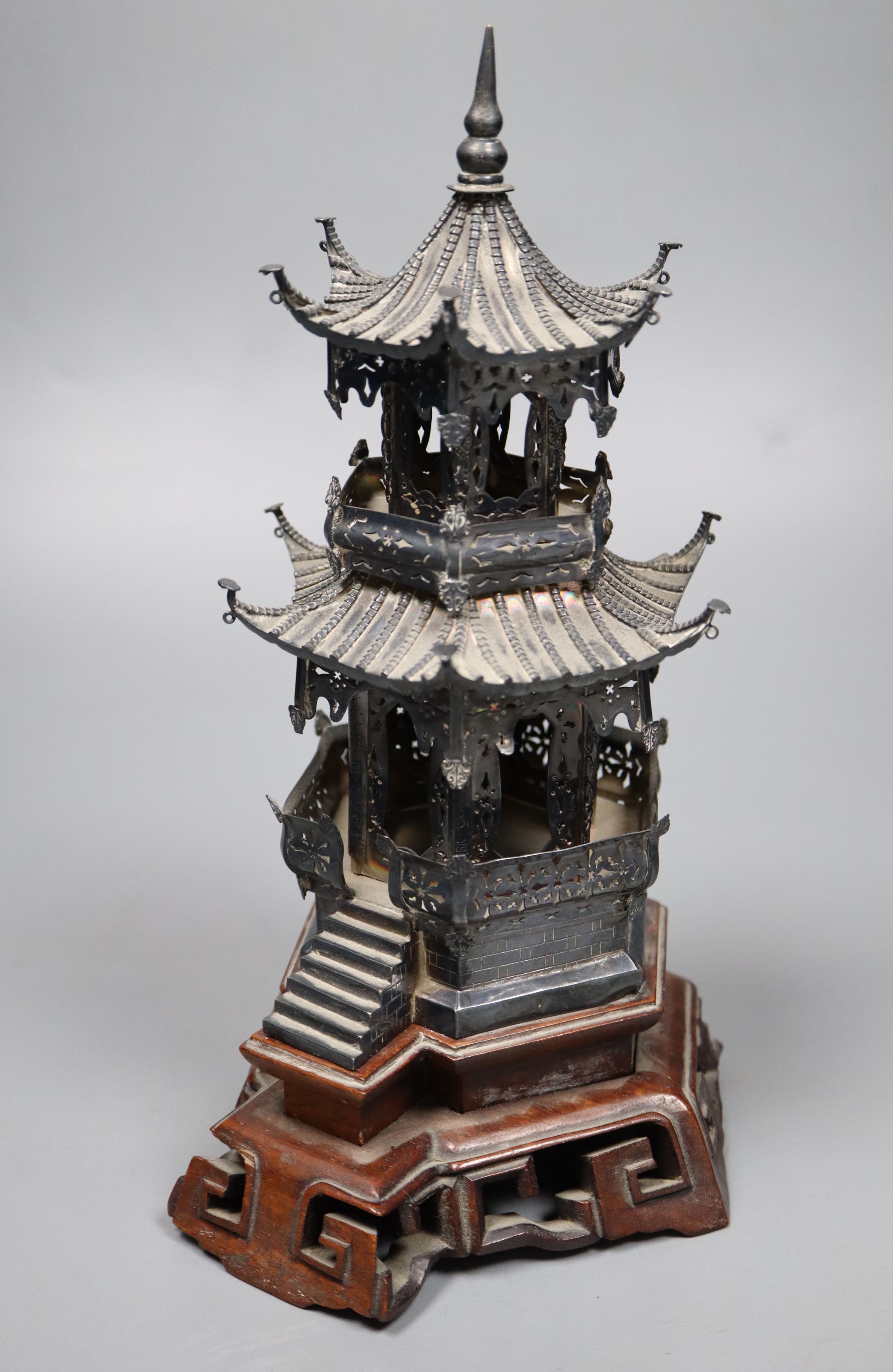 An early 20th century Chinese white metal miniature model of a pagoda, on a hardwood base, model 21.4cm, 11.5oz,